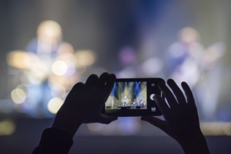 Fan holding smartphone and recording or taking picture during a concert