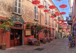 Luino, Italy, 16 March, 2023: cobblestone street with small shops and colorful decorations in the