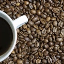 Roasted coffee beans and a cup of coffee on a table