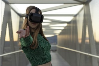 Young hispanic woman wearing in virtual reality goggles, touch something like push click on button,