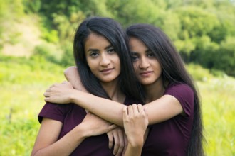 Adult female twins hugging each other - outdoor shot