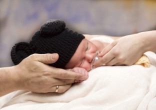 Newborn Baby Boy Sleeping on Parents Hands, over coloured background