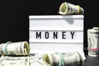 Lightbox board with the word MONEY in black letters around Us dollars banknotes. Finance background