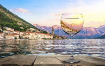 Wineglass on old wooden table on a background of Perast, Montenegro, Europe