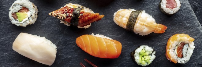 Sushi overhead flat lay panorama. Rolls, maki, nigiri on a black background, Japanese food. Salmon,