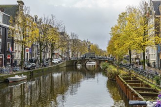 Canal with bridges and autumn atmosphere, surrounded by yellow leaves and city buildings,
