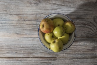 Apples in vintage metal cup on white wooden table
