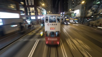 Traffic of public transport in night Hong Kong. Double-decker tram and buses driving in the city.
