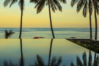 Delicate sunset on the popular resort island of Koh Samui. Palm trees reflected in smooth water of