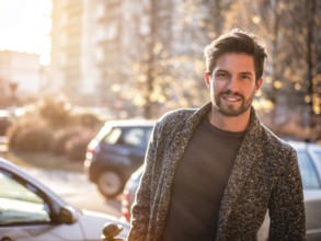 One handsome young man in urban setting in European city, standing in street near cars