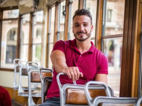 Young handsome man riding on tram or old bus in city, wearing polo shirt