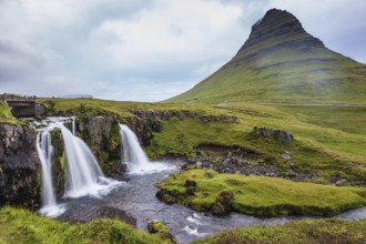 Cascade deep falls on the grassy mountains. Iceland - the country of mountains, the rivers and