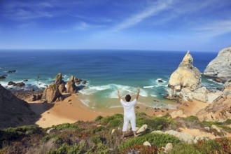 Small beautiful beach on the Atlantic coast. Middle-aged woman dressed in white doing yoga. The
