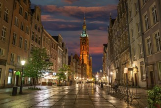Long street and the Main Town Hall in Gdansk, illuminated in evening