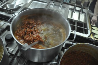 Shrimp boiling in a large pot on a stove in a busy kitchen setting, Cooks and chefs prepare dinner