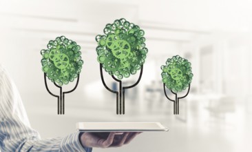 Close of businessman holding tablet pc with green tree made of gears and cogwheels. Mixed media