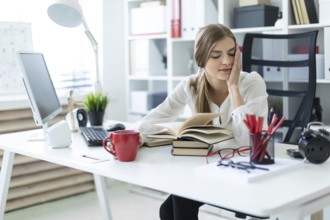 Beautiful young girl with blond hair. A girl in a white blouse and black pants is working in the