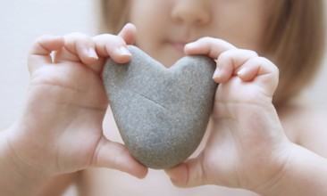 Child's hands hold heart from a stone
