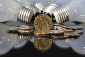 Wasteful bulbs and U.S. dollar coins on a black table