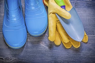 Leather safety gloves metal hand spade waterproof rubber boots on wooden board agriculture concept