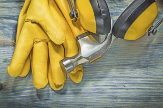 Leather yellow safety gloves ear muffs claw hammer on wooden board construction concept