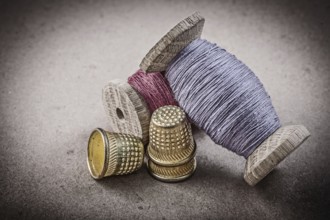 Spools of sewing threads thimbles on vintage background needlework concept