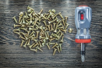 Screwdriver tapping screws on wooden board