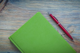 Notepad ball-point pen on wooden board top view education concept