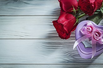 Metal heart-shaped gift box red roses on wooden board holidays concept
