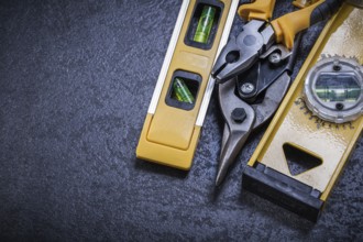 Tin snips pliers construction level on black background