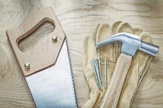 Claw hammer leather protective gloves handsaw nails on wooden board construction concept