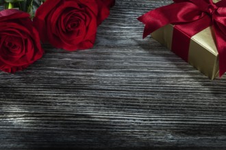 Golden gift box red roses on wooden board