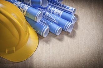Blue rolled blueprints building helmet on wooden board construction concept
