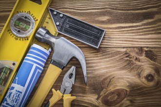 Blue blueprints construction level square ruler claw hammer pliers on wooden board