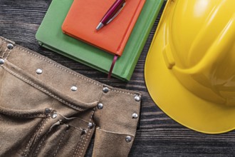 Tool belt notepads pen safety building helmet on wooden board construction concept