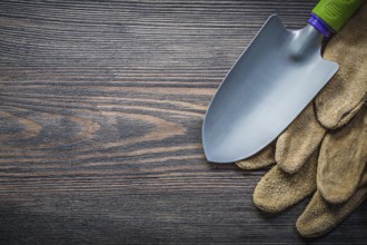 Trowel pair of leather safety gloves on wooden board directly above gardening concept