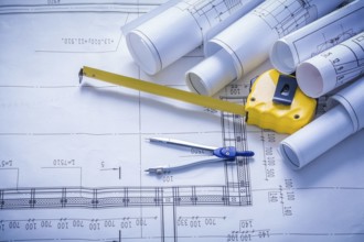 Rolled blueprints compass and yellow tapeline