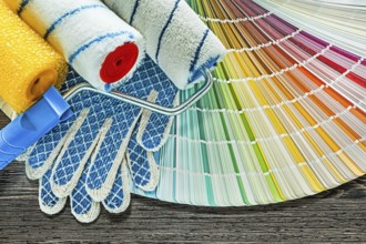 Paint rollers safety gloves color palette on wooden board