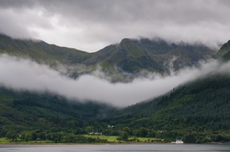 Idyllic mountain landscape with morning early fog covering the peaks at Fort Williams, Glencoe area