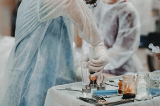 Medical staff in protective clothing operating a syringe on a sterile table