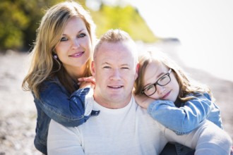 Family of three, mother father and daughter caually posing on the beach, Toronto, Canada, North