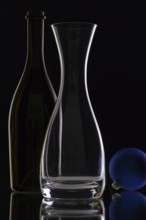 The bottle of wine, glass carafe and Christmas decoration on a black glass desk