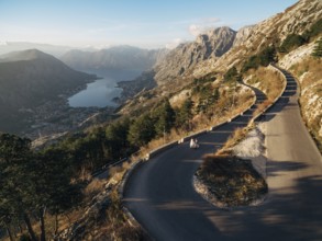 Bride and groom are walking along a high-mountain asphalt road over the bay.