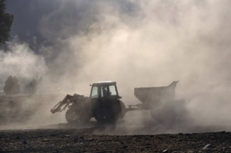 Tractor spreading lime with a fertiliser spreader, West Coast, New Zealand, Oceania
