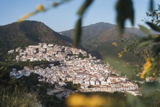 Warm evening light bathes the white village of Ojen, Spain, nestled in the lush mountains of