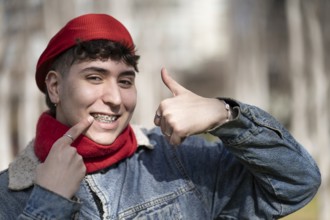 Young man smiling at the camera with thumb up showing his braces