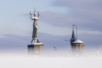 A large statue of Imperia and a small tower rise out of a misty winter landscape, Constance