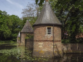Brick building with towers reflected in a pond covered with water lilies, ochtrup, münsterland,