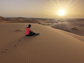 A caravan of dromedaries passing the Sahara desert in the evening, Erg Chebbi in Morocco