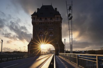 A road or motorway leads through an old historic city gate. Sunset in the evening over the Rhine
